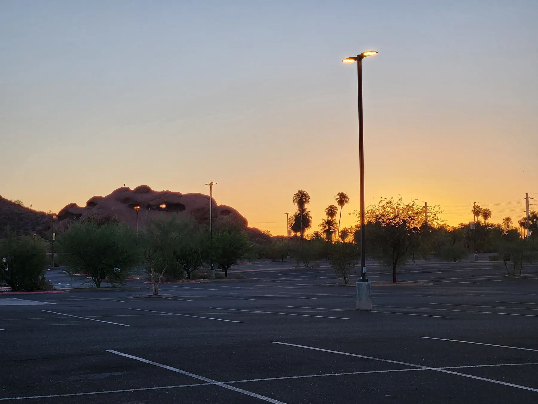 Sunrise behind Papago Park rock formations and an open parking lot