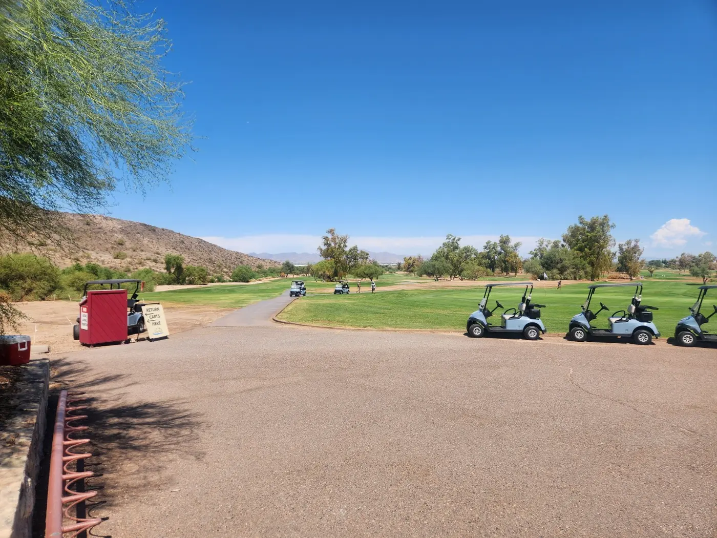 Tres Rios Golf Course with golf carts, green fairway and the Estrella Mountains